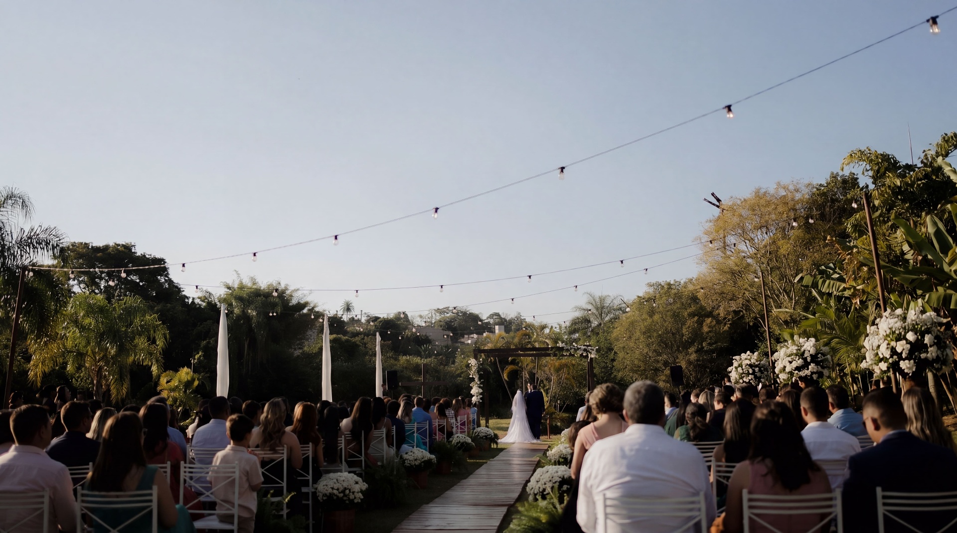 Cerimônia de casamento ao ar livre no Laurus Eventos com convidados, varal de luzes e altar floral em Betim, MG